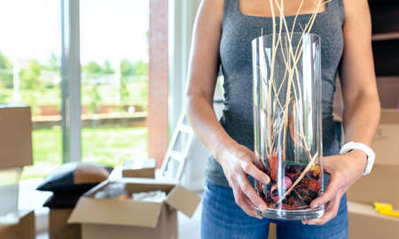 Unrecognizable woman doing a move showing a vase with dry branches
