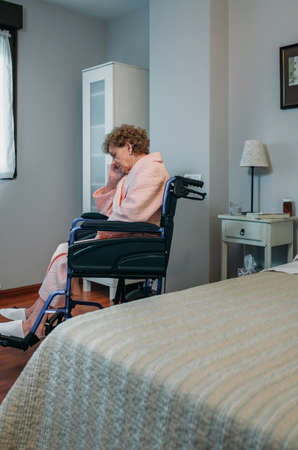 Senior woman in a wheelchair alone in a roomの写真素材