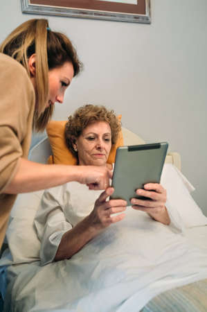 Female doctor showing results of a medical test on the tablet to female senior patientの写真素材