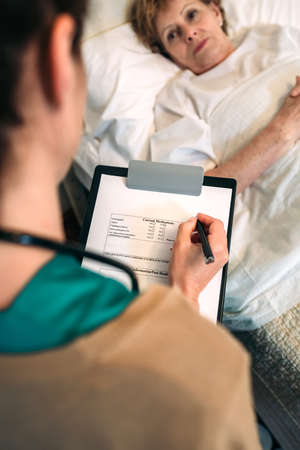 Female doctor filling out a questionnaire to a senior patientの写真素材