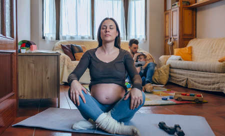 Pregnant woman exercising in the living room of her houseの写真素材