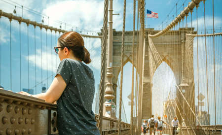 Woman with sunglasses looking cityscape from Brooklyn Bridge with Manhattan skyline on background, in New York Cityの写真素材