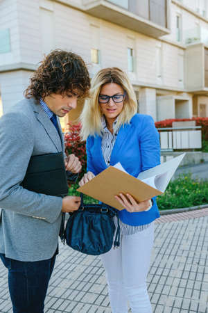 Businessman and businesswoman checking documents in the streetの写真素材