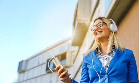 Businesswoman with headphones and mobile in the streetの写真素材