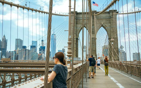 NEW YORK CITY, USA - JUNE 21, 2016: Tourists taking photos in Brooklyn Bridge with Manhattan skyline on background, in New York Cityのeditorial素材