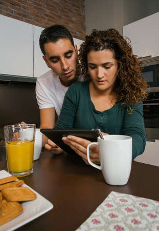Couple having breakfast in the kitchen and looking at the tabletの写真素材