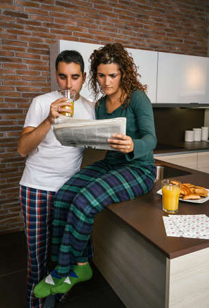 Couple having breakfast in the kitchen and reading the newspaperの写真素材