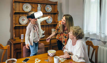 Senior woman using virtual reality glasses with her daughter and granddaughterの写真素材
