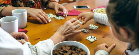 Unrecognizable grandmother, daughter and granddaughter playing domino in the living roomの写真素材
