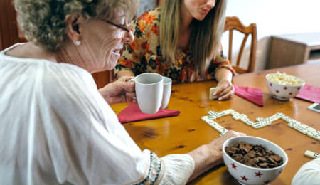 Senior mother and daughter playing domino in the living roomの写真素材