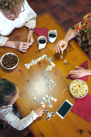 Top view of grandmother, daughter and granddaughter playing domino in the living room