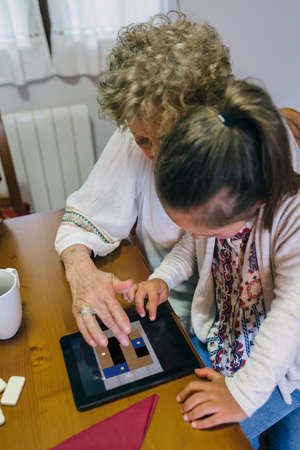 Grandmother and granddaughter playing with the tablet in the living roomの写真素材