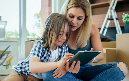 Mother and son playing the tablet sitting on the carpetの写真素材