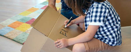 Little boy writing his name in a moving box with his fatherの写真素材
