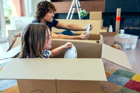 Father and son playing car racing with cardboard boxes in the living room