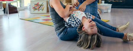 Parents tickling their son on a break from movingの写真素材