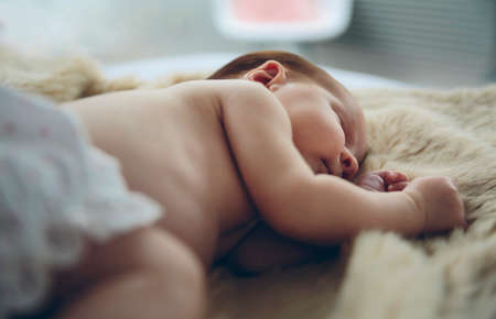 Newborn baby girl sleeping lying on a blanket on the bedの写真素材