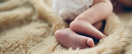 Detail of newborn baby feet lying on a blanket on the bedの写真素材