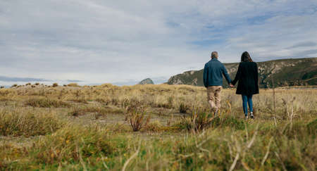 Unrecognizable young couple backwards taking a walk near the coastの写真素材