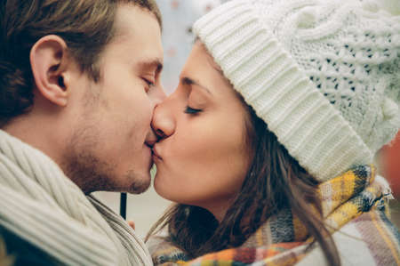 Closeup of young beautiful couple kissing under the umbrella in an autumn rainy day. Love and couple relationships concept.の写真素材