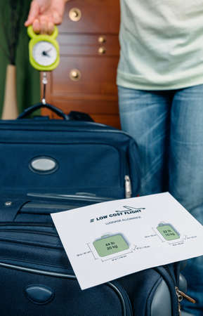 Woman checking hand luggage weight using a steelyard balance by low cost airlines restrictions