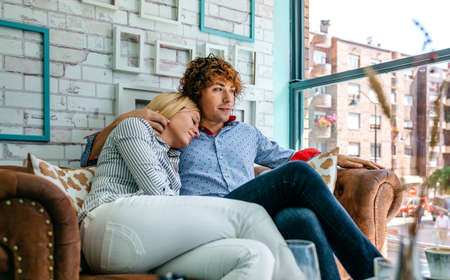 Man and woman hugging on a sofa in a coffee shop