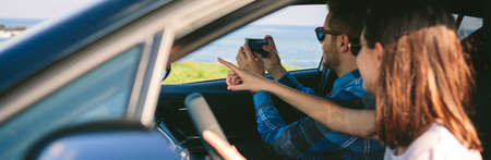 Couple traveling taking a picture of the landscape with the mobile from the carの写真素材