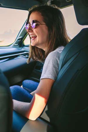 Young happy girl with sunglasses laughing in the carの写真素材
