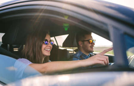 Happy young man driving a car accompanied by his girlfriend