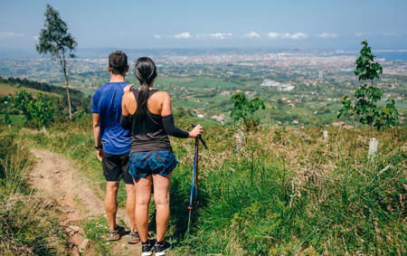Young couple stopping to look at the views of the city while doing trail