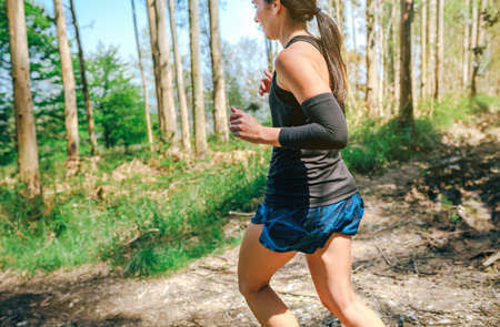 Young woman participating in a trail race through the forestの写真素材