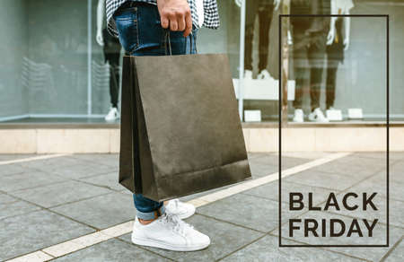 Legs of unrecognizable young man shopping with paper bags in his hand. Black friday conceptの写真素材