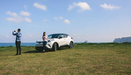 Young couple traveling by car making a stop to photograph the landscape