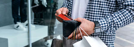 Young man with shopping bags taking out credit card from walletの写真素材