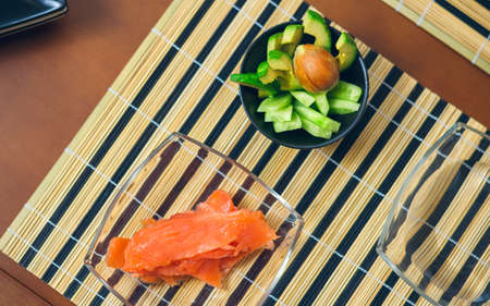 Top view of bowls with avocado, cucumber and salmon cut ready to prepare sushiの写真素材