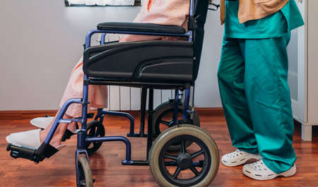 Female doctor carrying elderly female patient in a wheelchairの写真素材