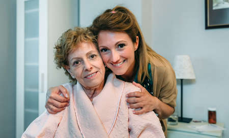 Affectionate female caretaker posing with elderly female patient