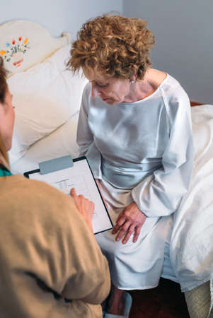 Female doctor filling out a questionnaire to a senior patientの写真素材