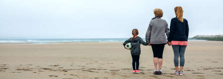 Back view of three generations female watching the sea in autumn