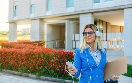 Businesswoman with headphones and mobile in the street