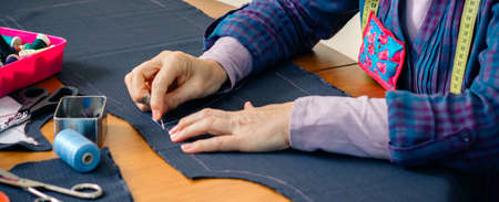 Senior female seamstress sewing cloth to make a garment in her workshop