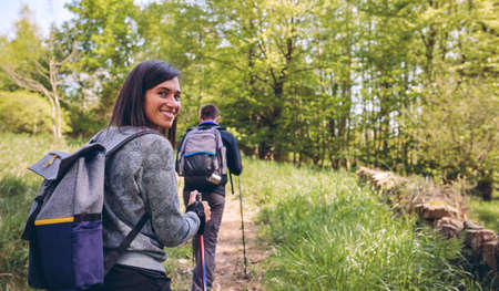 Young woman doing trekking looking at camera with guy in the backgroundの写真素材
