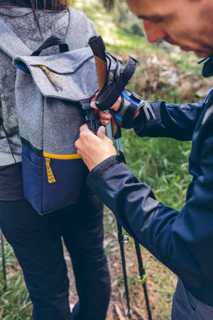Male hiker closing his partners backpack while trekking