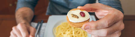Man ready to eat crickets and cheese canapeの写真素材