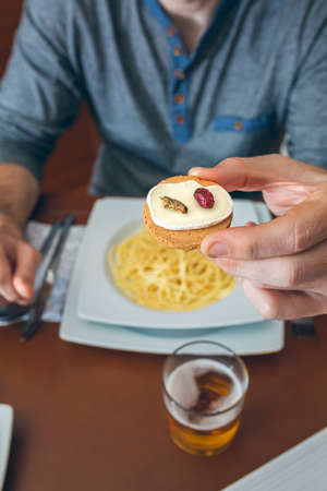 Man ready to eat crickets and cheese canape