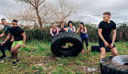 Group of female participants in an obstacle course turning a truck wheelの写真素材