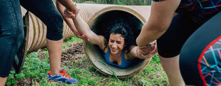 Female participants in an obstacle course going through a pipeの写真素材