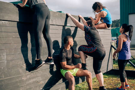 Group of participants in an obstacle course climbing a wallの写真素材