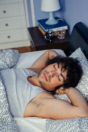 Young man deep asleep in bed at home