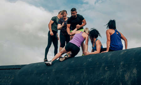 Group of participants in an obstacle course climbing a drumの写真素材